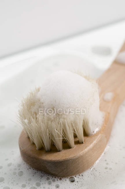 Close-up of bath brush in soap foam — Stock Photo
