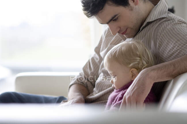 Man with little boy sitting on a sofa, side view — Stock Photo