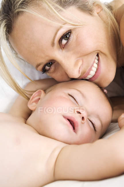 Ritratto di madre sorridente e bambino addormentato sul letto — Foto stock