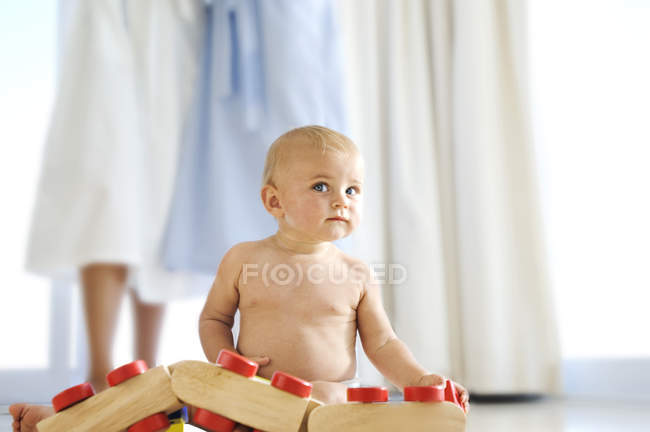 Без сорочки хлопчик грає вдома з дерев'яною іграшкою — стокове фото