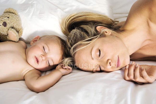 Portrait of baby boy and mother sleeping on bed — Stock Photo