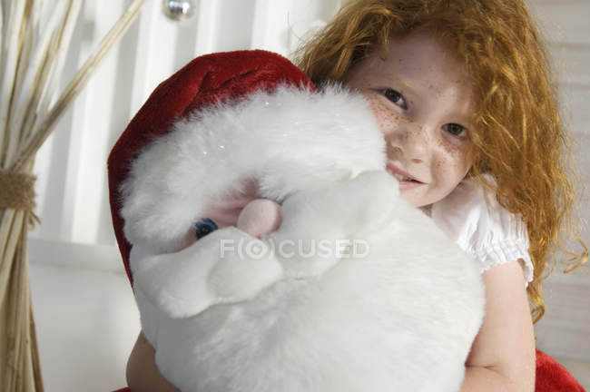 Retrato de jengibre niña sosteniendo un juguete de Santa Claus tierno - foto de stock