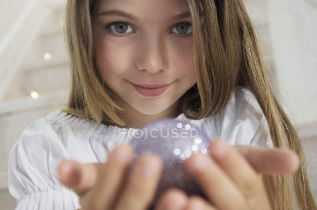 Портрет маленькой девочки, позирующей с рождественским мячом в помещении — стоковое фото
