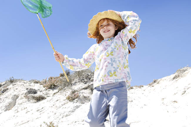 Little girl walking on beach, holding landing net, outdoors — Stock Photo