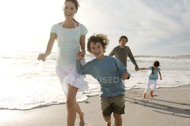 Pais e duas crianças caminhando na praia, ao ar livre — Fotografia de Stock