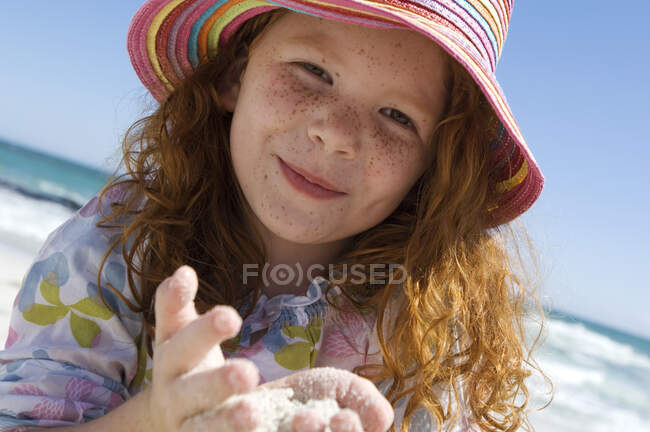 Портрет маленької дівчинки, яка посміхається дивиться на камеру, пісок в її руках, на відкритому повітрі — стокове фото