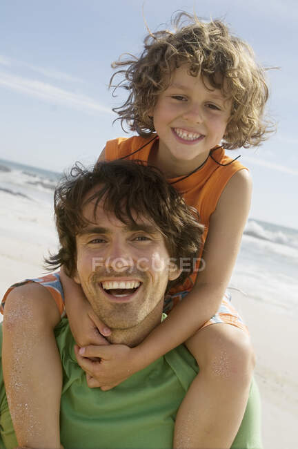 Portrait d'un père portant son fils sur ses épaules, à l'extérieur — Photo de stock