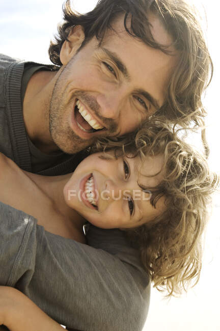 Retrato de un padre y un hijo sonriendo, mirando a la cámara, al aire libre - foto de stock