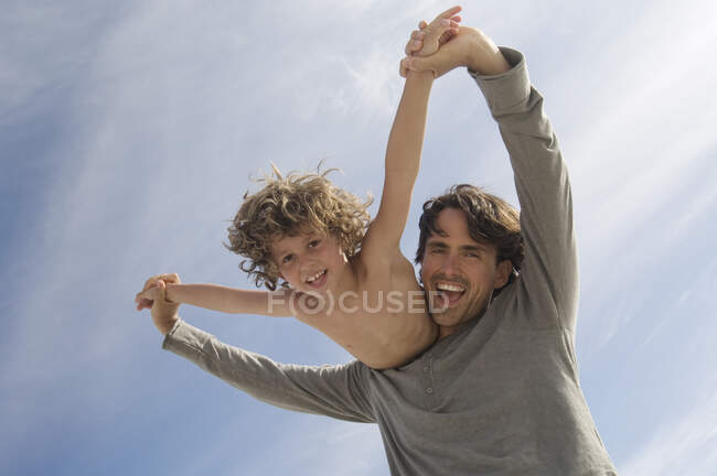Portrait d'un père portant son fils sur le dos, à l'extérieur — Photo de stock