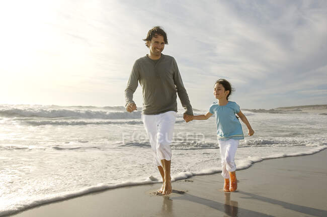 Отец и дочь гуляют по пляжу, на открытом воздухе — стоковое фото