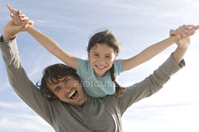 Portrait d'un père portant sa fille sur son épaule, à l'extérieur — Photo de stock