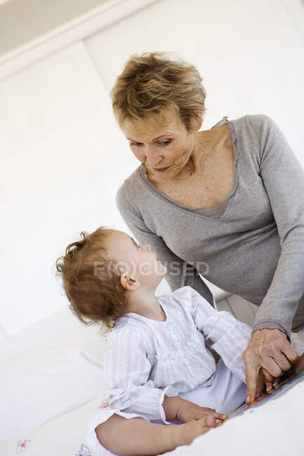 Femme âgée avec petite fille au lit — Photo de stock