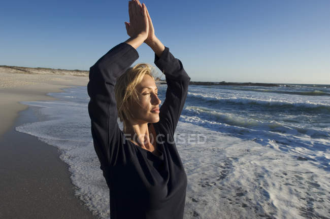 Entspannte junge Frau in Yoga-Haltung am Strand — Stockfoto