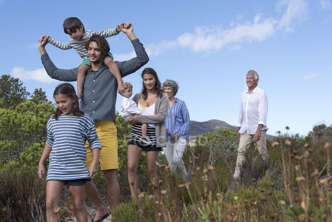 Feliz familia multi-generación caminando por el paisaje - foto de stock
