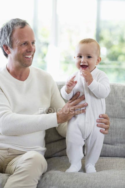 Père heureux jouant avec bébé fille mignonne dans le salon — Photo de stock