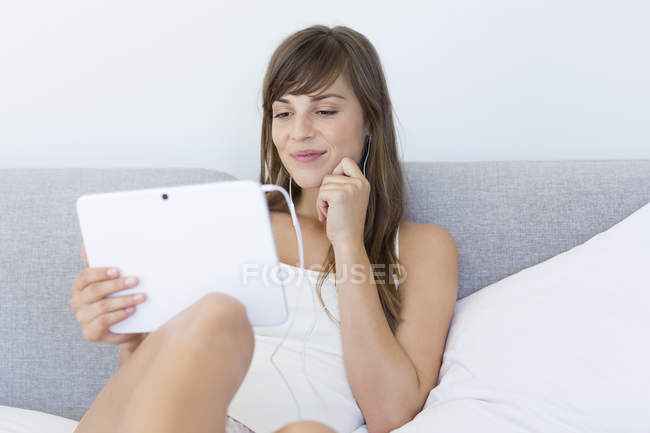 Young woman watching movie on digital tablet in bed — Stock Photo