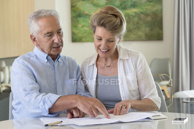 Seniorenpaar erledigt Papierkram zu Hause am Tisch — Stockfoto