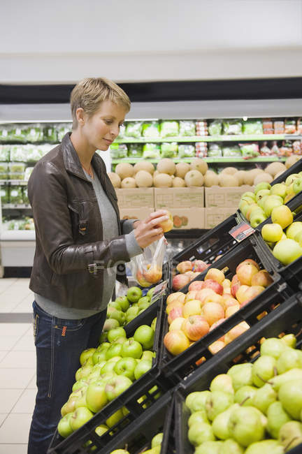 Woman with short hair buying apples in supermarket — Stock Photo