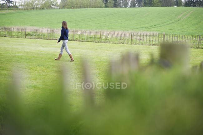 Adolescent fille marche sur vert champ — Photo de stock