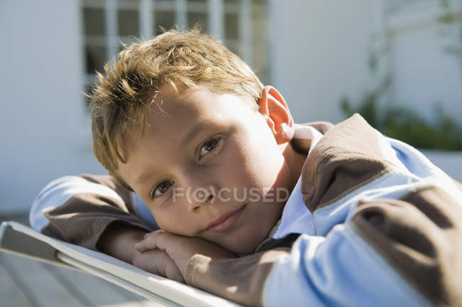 Portrait of pensive boy resting on deck chair outdoors — Stock Photo