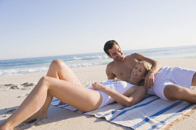 Pareja de risa relajada descansando en la playa de arena - foto de stock