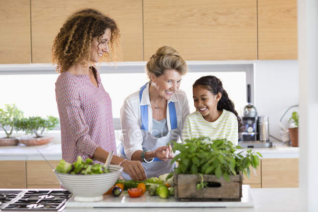 Femme âgée avec fille et petite-fille préparant la nourriture dans la cuisine — Photo de stock