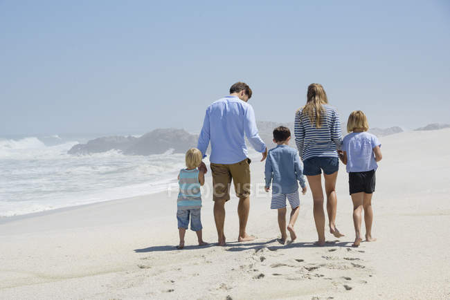 Вид на семью, гуляющую вместе на песчаном пляже — стоковое фото