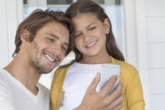 Buon padre con la piccola figlia che si fa selfie con la fotocamera del telefono a casa — Foto stock