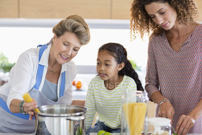 Mulher sênior com filha e neta preparando comida na cozinha — Fotografia de Stock