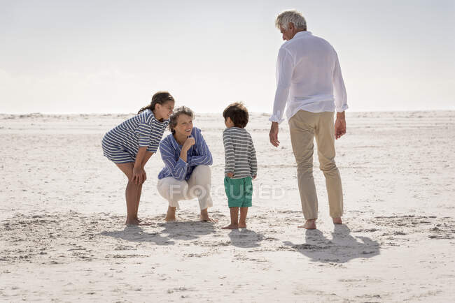 Felice nonni con nipoti godendo sulla spiaggia — Foto stock