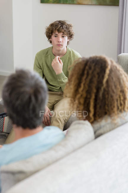 Family talking while sitting on sofa in living room at home — Stock Photo