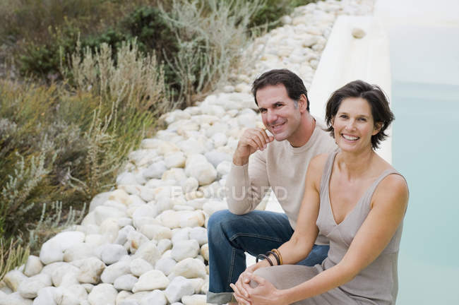 Portrait of happy couple smiling at poolside together — Stock Photo