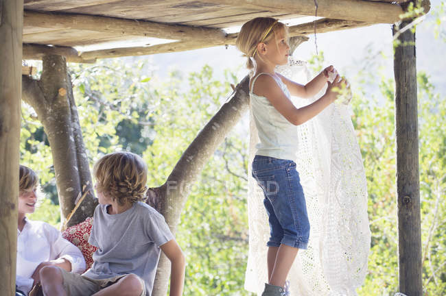 Niños jugando en la casa del árbol en el jardín de verano - foto de stock