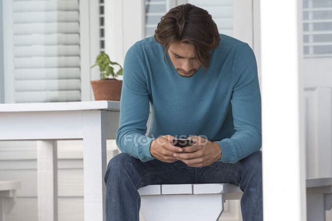 Jeune homme utilisant un téléphone portable à la maison — Photo de stock