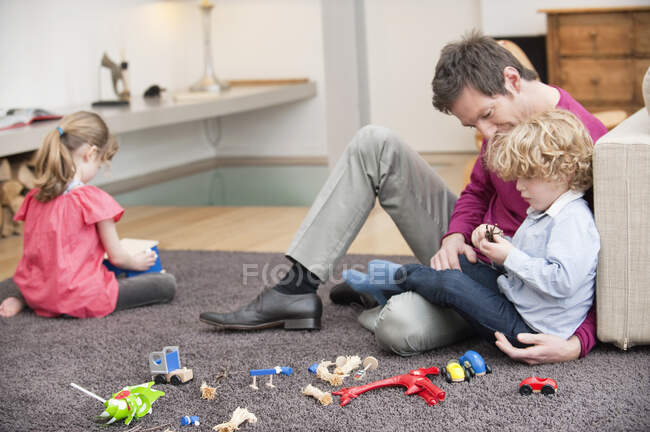 Homme jouant avec son fils dans un salon — Photo de stock
