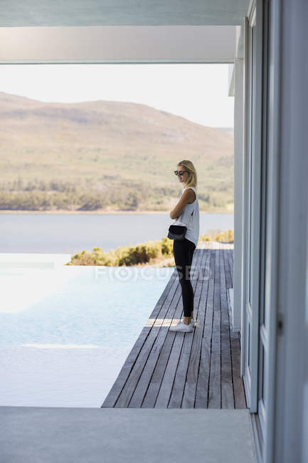 Perfil da jovem mulher de pé no calçadão na margem do lago e olhando para a vista — Fotografia de Stock