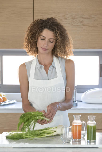 Mulher que arranja o funcho na mesa na cozinha — Fotografia de Stock