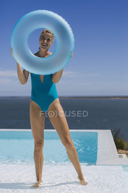 Щаслива молода жінка тримає надувне кільце біля басейну — стокове фото