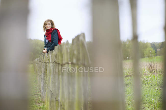 Jovem com cachecol vermelho andando em campo — Fotografia de Stock
