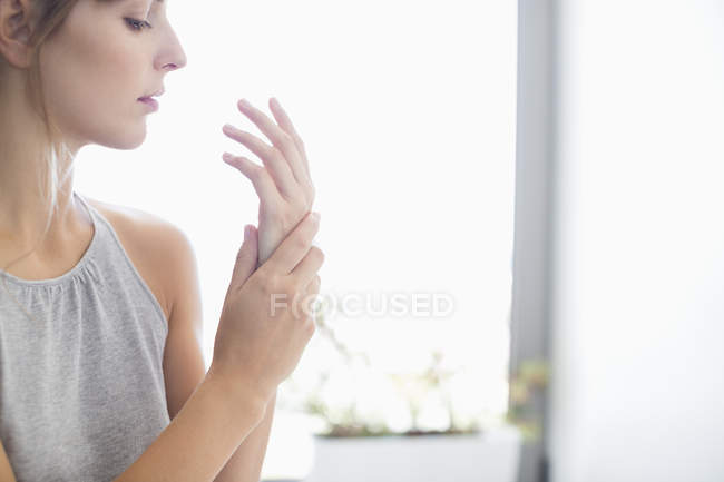 Primo piano della donna che applica la crema idratante sulle mani — Foto stock