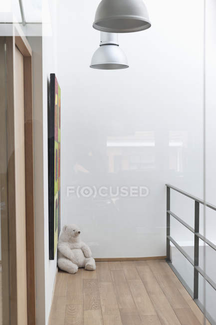 Urso de pelúcia no chão de madeira no canto da casa moderna — Fotografia de Stock