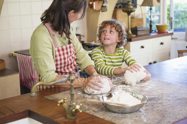 Großmutter und kleiner Junge kneten Teig in Küche — Stockfoto