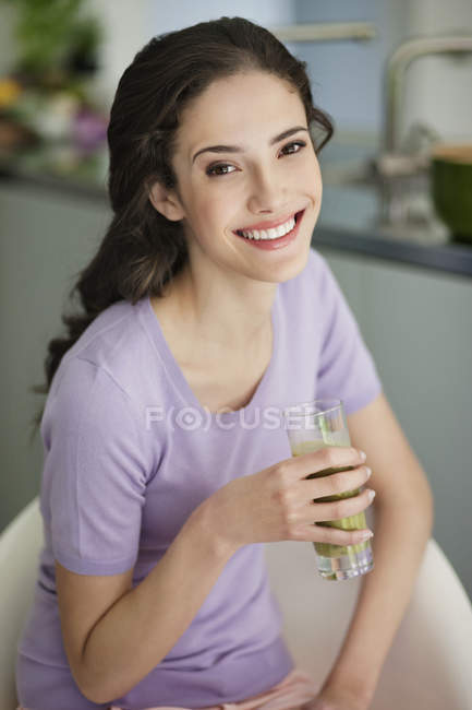 Frau hält Glas Gemüsesmoothie und lächelt — Stockfoto