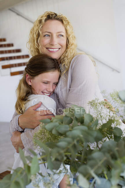 Середня доросла жінка обіймає доньку і посміхається — стокове фото