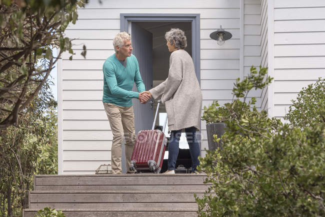 Homme âgé accueillant femme à la porte — Photo de stock