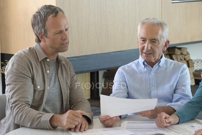 Senior erledigt Papierkram mit Sohn im Wohnzimmer — Stockfoto