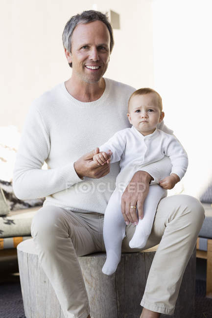 Retrato de pai feliz com bebê bonito filha sentada na sala de estar — Fotografia de Stock