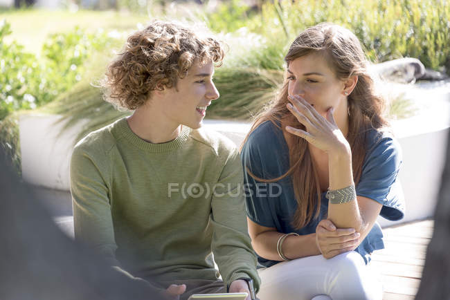 Heureux frère et sœur assis dans le jardin et parlant — Photo de stock