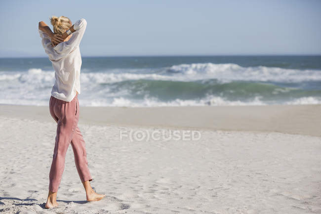 Расслабленная блондинка, стоящая на солнечном пляже — стоковое фото