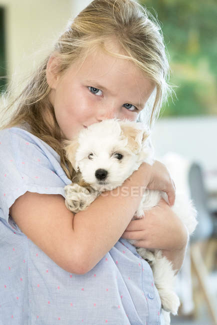 Retrato de linda niña sosteniendo cachorro - foto de stock